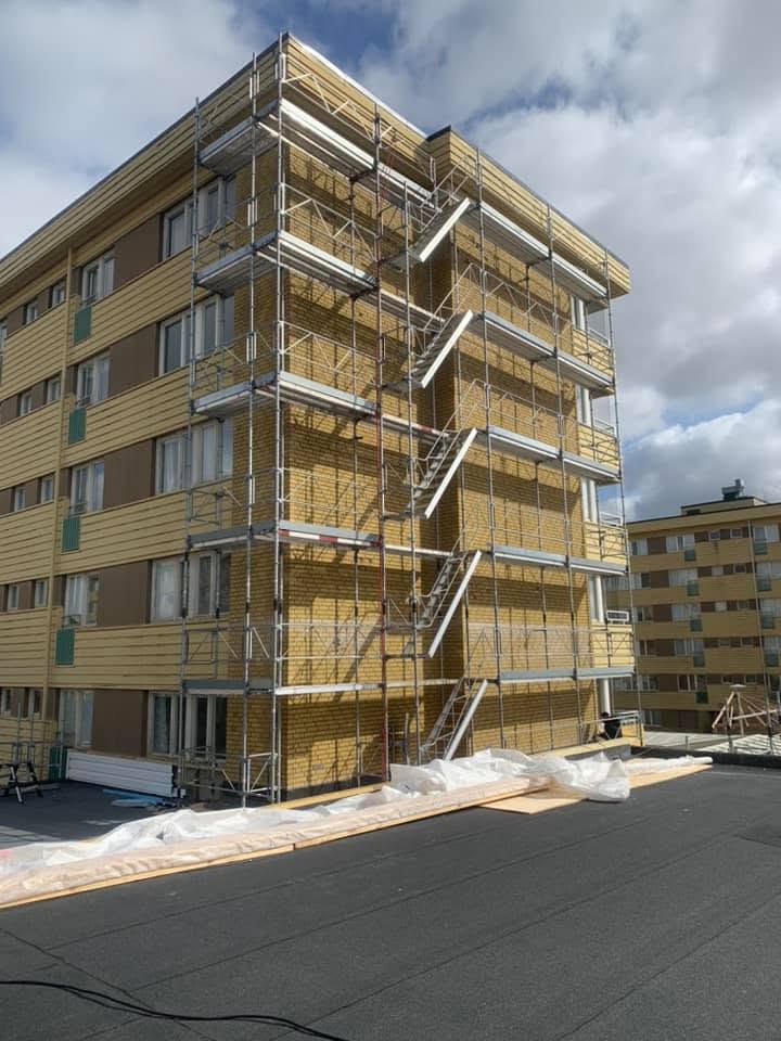 Fasadställning med trapptorn på ett gult flerbostadshus