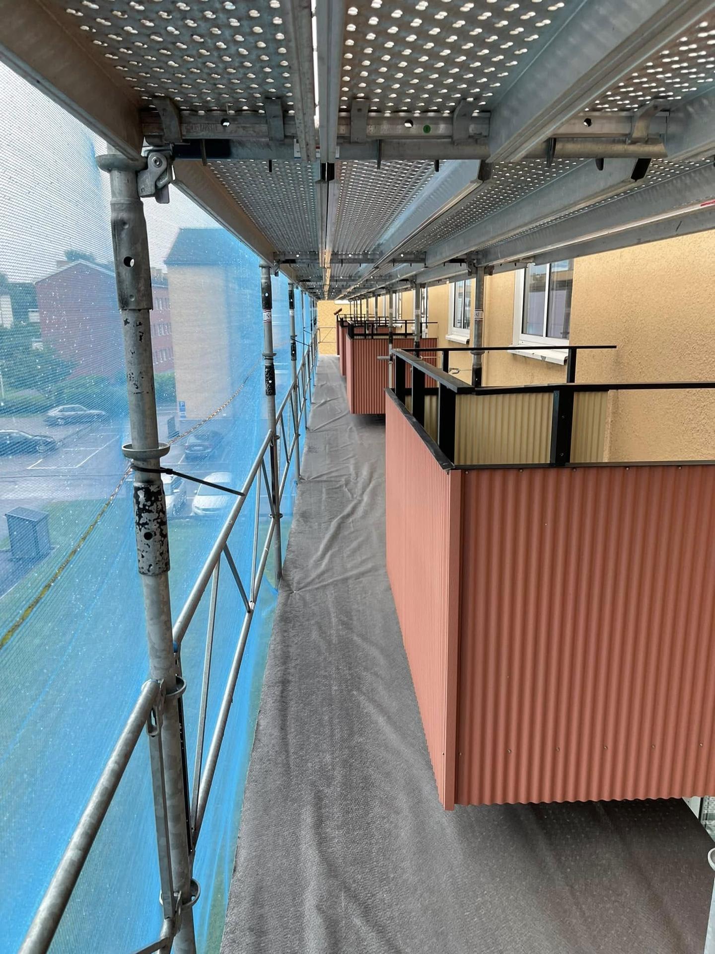 Arbetsplan i ställning med skyddsnät längs balkongerna på ett flerbostadshus