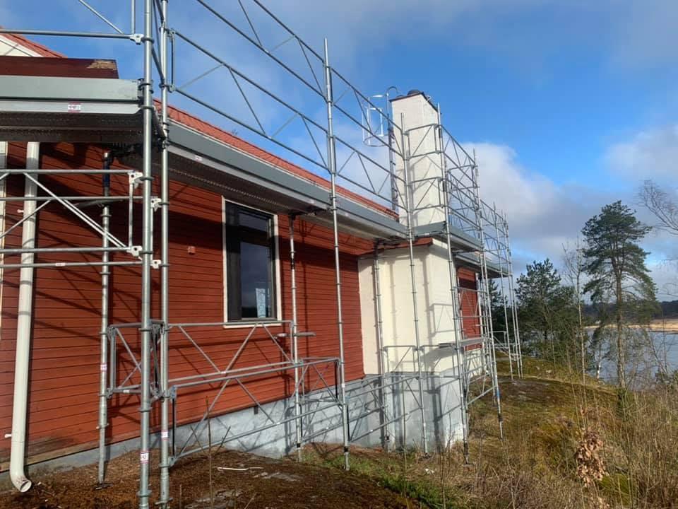 Ställning runt ett rött trähus vid takbyte utanför Uddevalla